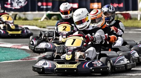 5 race car drivers in race car helmets racing each other