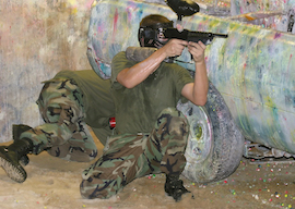 man dressed in all green shooting paintball gun