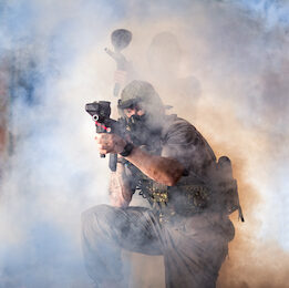 man playing paintball shooting gun in smoke