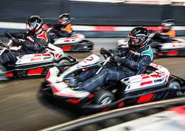 4 men racing race cars in helmets on race track